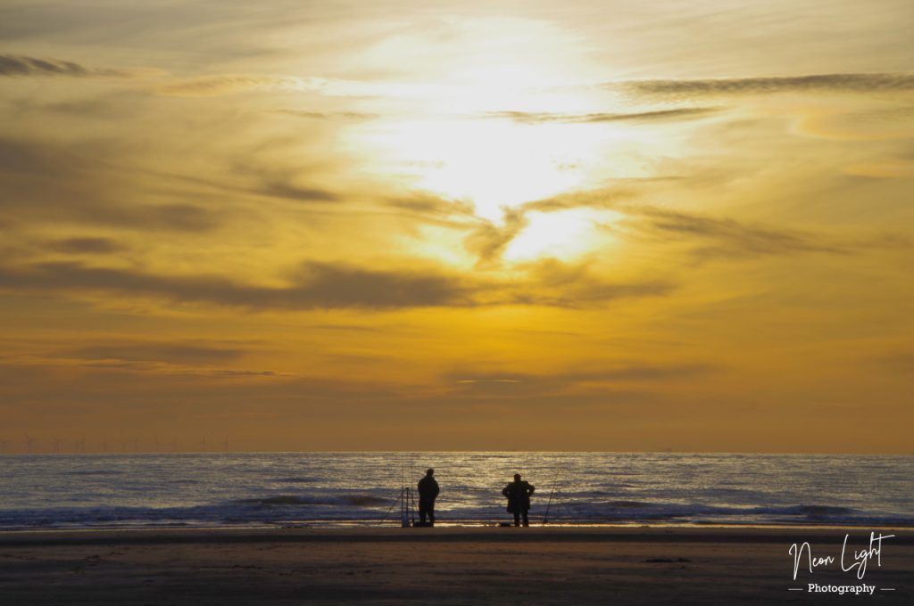 Sea fishermen wait for a catch as the tide recedes on the beach
