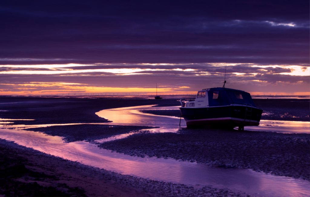 The sun sets at Meols shore, reflecting in the channels emptying the tide back into the Irish Sea.